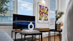 Ein modernes Wohnzimmer mit einem großen Flachbildfernseher, einem gerahmten abstrakten Gemälde und einem Blumentopf.