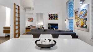 A modern living room with a sofa, a dining table with a bowl of decorative balls, a ladder, and artwork on the walls. - LiV MTL Main Plateau Urban Suites Near Downtown Montreal (Montréal)