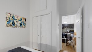 A bedroom with a bed, a white wardrobe, and a door leading to a kitchen. - LiV MTL Main Plateau Urban Suites Near Downtown Montreal (Montréal)
