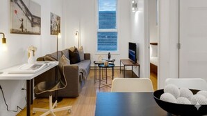 A modern living room with a sofa, coffee table, TV, and artwork on the wall.