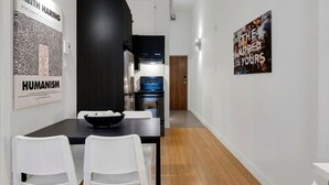 A modern interior with a dining area, kitchen, and artwork on the walls.