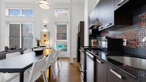 Una cocina moderna con armarios oscuros, un lavamanos de acero inoxidable y un salpicadero de azulejos.