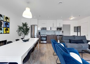 Een moderne keuken met een eethoek, een grijze bank en een blauwe stoel.