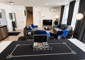 A modern living room with a sofa, a television, and a coffee table. - Spacious 3BR Penthouse Rooftop • Sleeps 12 (Montréal)
