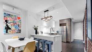 Una cocina moderna con una isla central, taburetes de bar y un refrigerador de acero inoxidable.