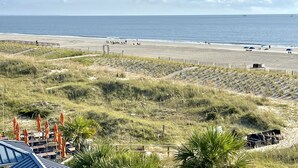 A beach with a wooden walkway, grassy dunes, and a distant view of the ocean. - Summer & July 4th Savings at Beachside Colony Tybee's ONLY Oceanfront Resort 1/1 (tybee island)