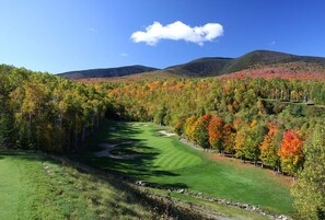 A golf course with a clear path, surrounded by autumn-colored trees and hills in the background. - Sugarloaf Mt. - on the mountain, pool/hot tub/sauna, short walk to lift, quiet (Carrabassett Valley)