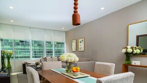 A modern dining area with a wooden table, cushioned chairs, and a vase of flowers.