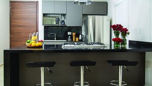 A modern kitchen with a black countertop, stainless steel appliances, and a vase with red flowers.