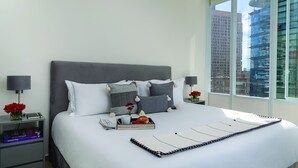 A modern hotel room with a large bed, two bedside tables, and a view of a cityscape.