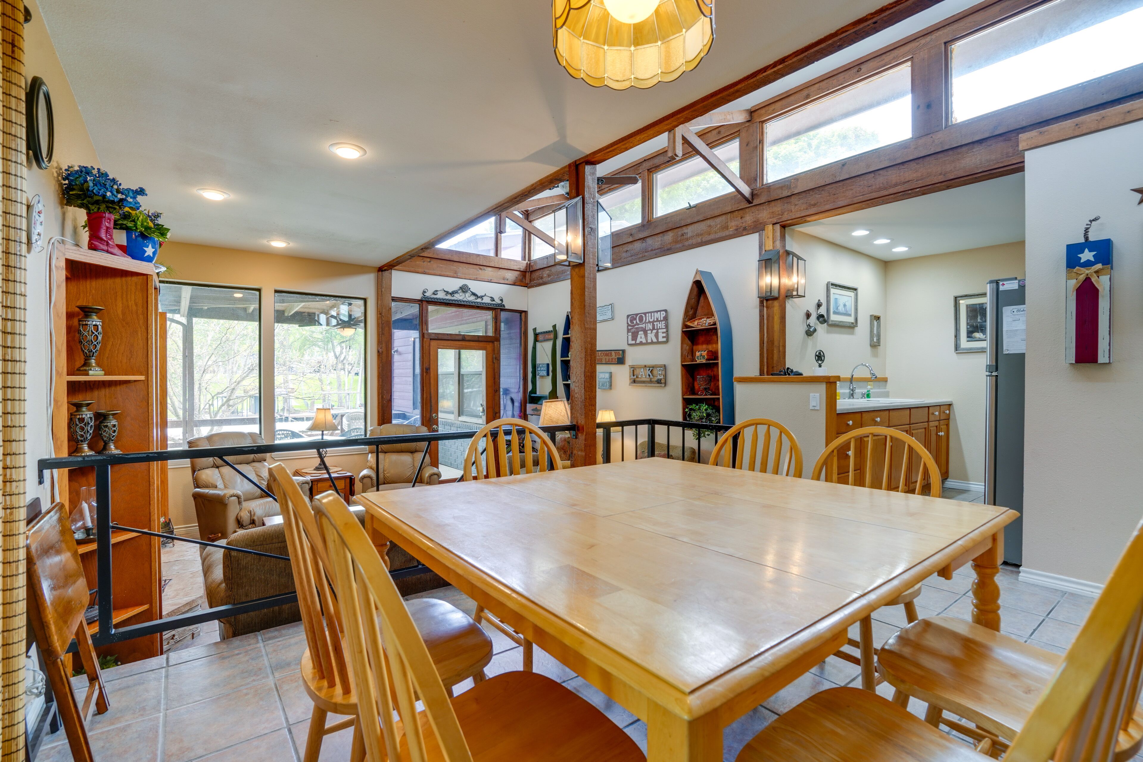 A spacious dining area with a large wooden table and chairs, surrounded by windows and a view of the outdoors.