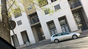 Um edifício moderno com várias varandas e um carro estacionado na rua.