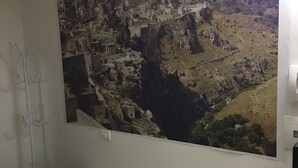 Quarto com uma cama, um mural grande na parede retratando uma cidade e uma janela.