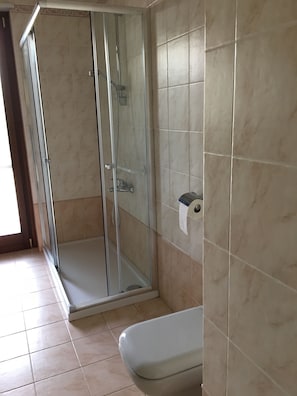 A bathroom with a glass-enclosed shower, a toilet, and tiled walls. - La Tua Casa a Matera (Matera)
