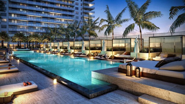 A modern hotel pool area with sun loungers and a glass-enclosed cabana.