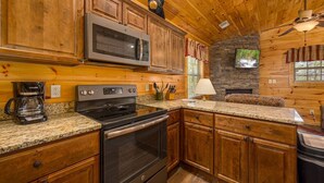 A kitchen with wooden cabinets, a microwave, a stove, and a coffee maker. - Heavenly View – Romantic Pigeon Forge Cabin with Hot Tub, Jacuzzi & Pool Table (Sevierville)