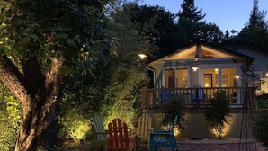 Talo, jossa on terassi, ja sen ympärillä on puita sekä tiilestä rakennettu patio.