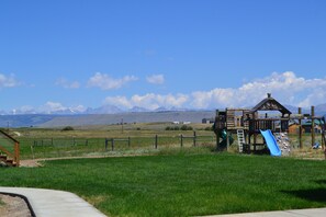 A playground with a slide and climbing structures, set in a grassy field with mountains in the background. - Quiet Guest House close to Pinedale with Mountain View (Pinedale)