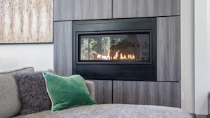 A modern living room with a fireplace, grey sofa, and a green throw pillow. - Scenic Wonders Adventure Lodge 3 Bedroom (Yosemite National Park)