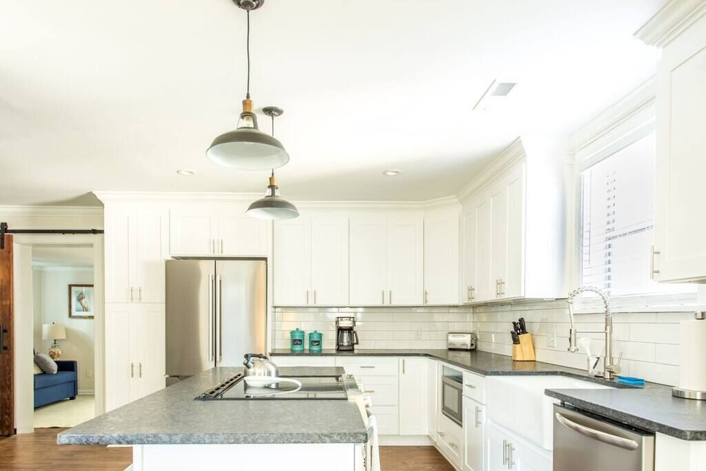 Una cocina moderna con armarios blancos, encimera de granito y electrodomésticos de acero inoxidable.