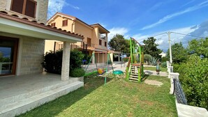 Um imóvel residencial com um pátio, área de recreação com balanço e gramado bem cuidado.