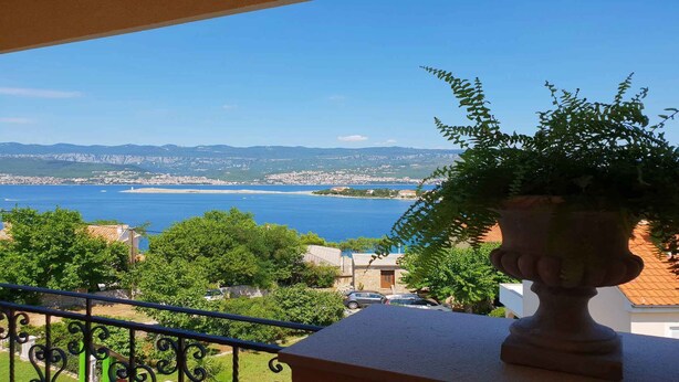 Uma varanda com vista para uma cidade costeira e o mar.