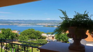 A balcony with a view of a coastal town and the sea. - Holiday apartment with balcony and panoramic view (Šilo)