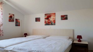 Hotellihuone, jossa on kaksi sänkyä, sängynpääty ja kolme taulua seinällä.