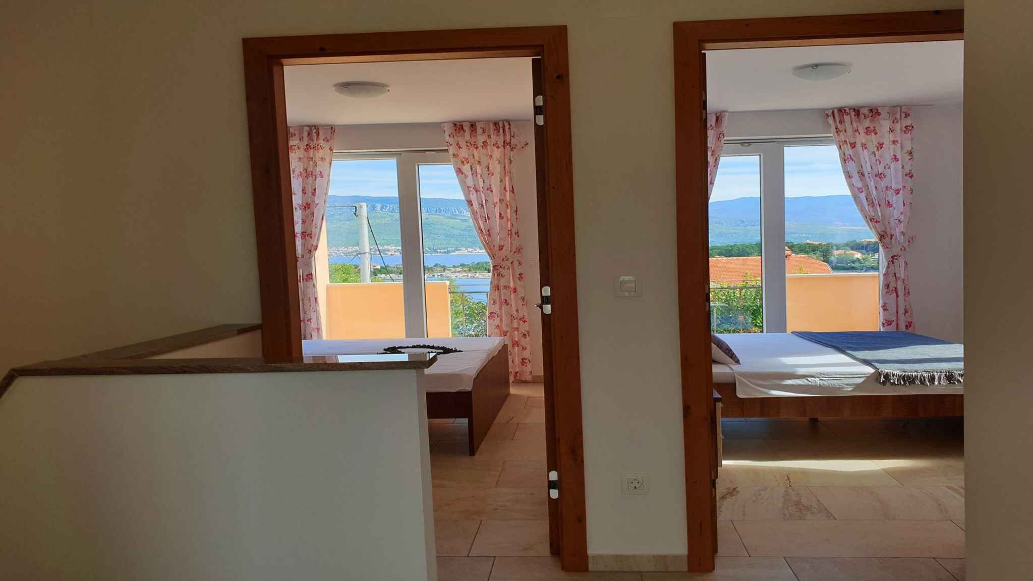 Una habitación con cama y escritorio, vista al mar y balcón con barandilla.