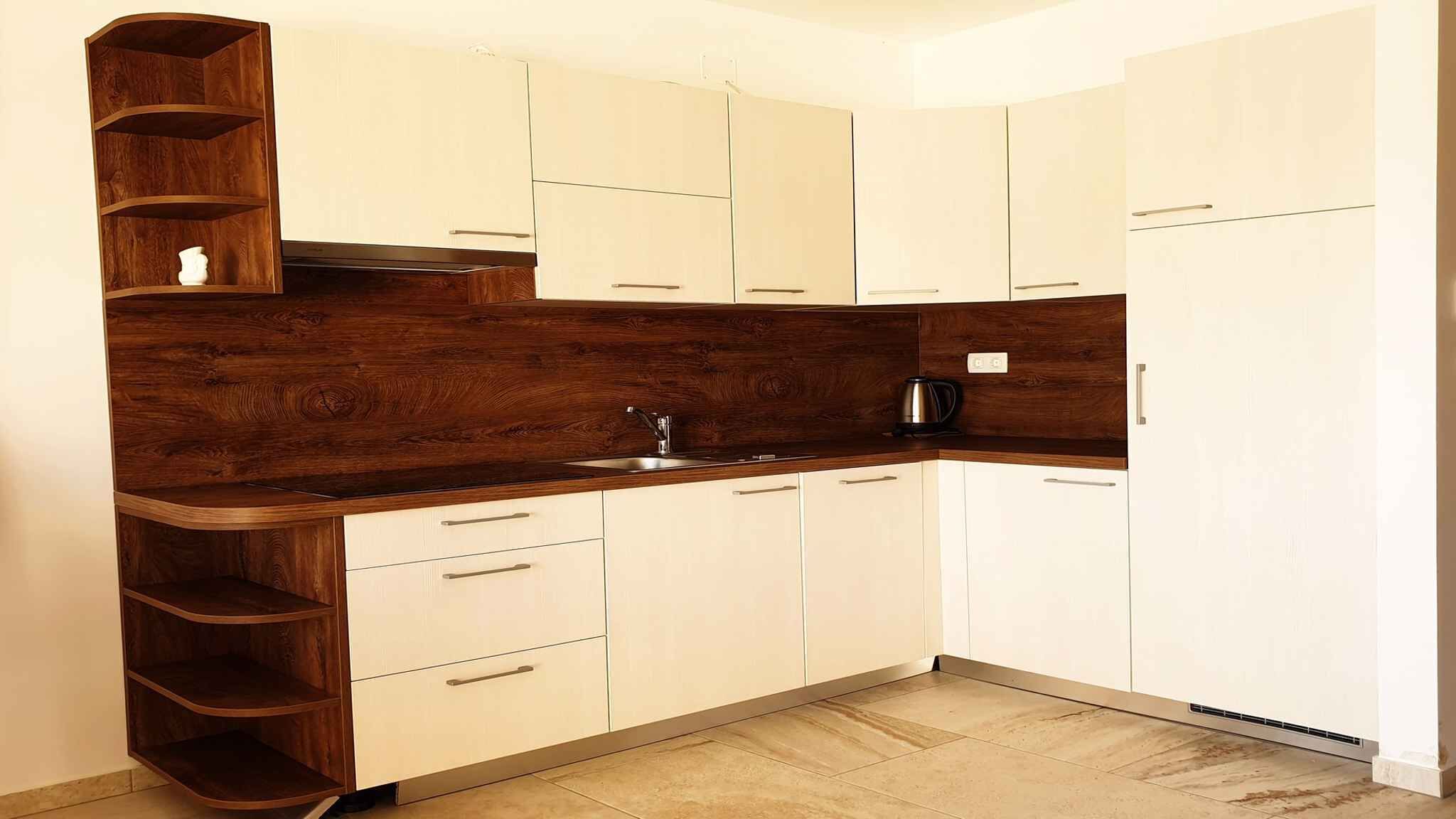 A compact kitchen with white cabinets, a wooden countertop, and a built-in shelf unit.