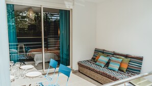 A balcony with a dining table set for four, blue chairs, and a wicker sofa with colorful cushions. - Magnificent F1 Apartment, The Coral Garden, in the Heart of Saline les Bains (La Saline-Les-Bains)