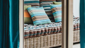 A wicker sofa with striped cushions and a woven throw blanket. - Magnificent F1 Apartment, The Coral Garden, in the Heart of Saline les Bains (La Saline-Les-Bains)