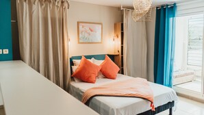 A bedroom with a bed, curtains, a hanging light fixture, and a window with a view. - Magnificent F1 Apartment, The Coral Garden, in the Heart of Saline les Bains (La Saline-Les-Bains)