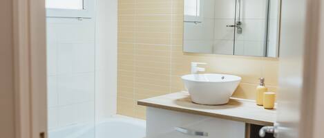 Un baño con bañera, lavamanos, espejo y retrete.