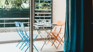 A dining area with a table set for four, blue and orange chairs, and a view of greenery outside. - Magnificent F1 Apartment, The Coral Garden, in the Heart of Saline les Bains (La Saline-Les-Bains)