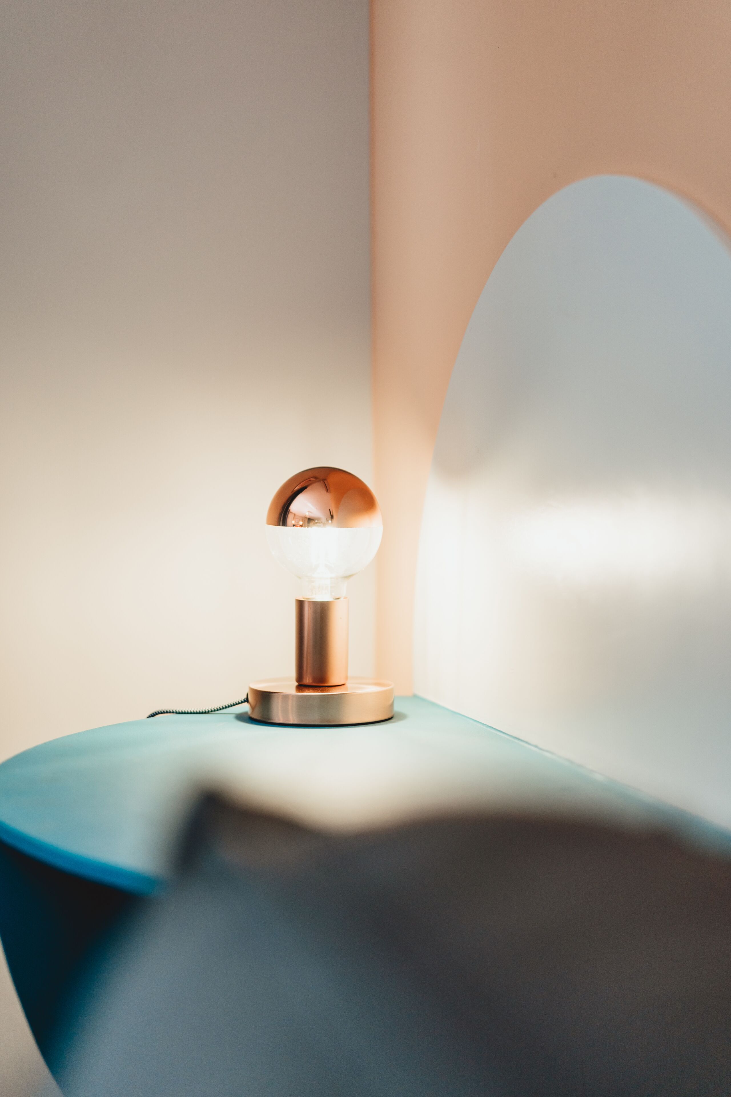Eine moderne Lampe mit einer kugelförmigen Schirm auf einer blauen Fläche.