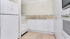 A compact kitchen with white cabinets, a built-in oven, and a microwave.