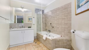 A modern bathroom with a bathtub, toilet, and sink.