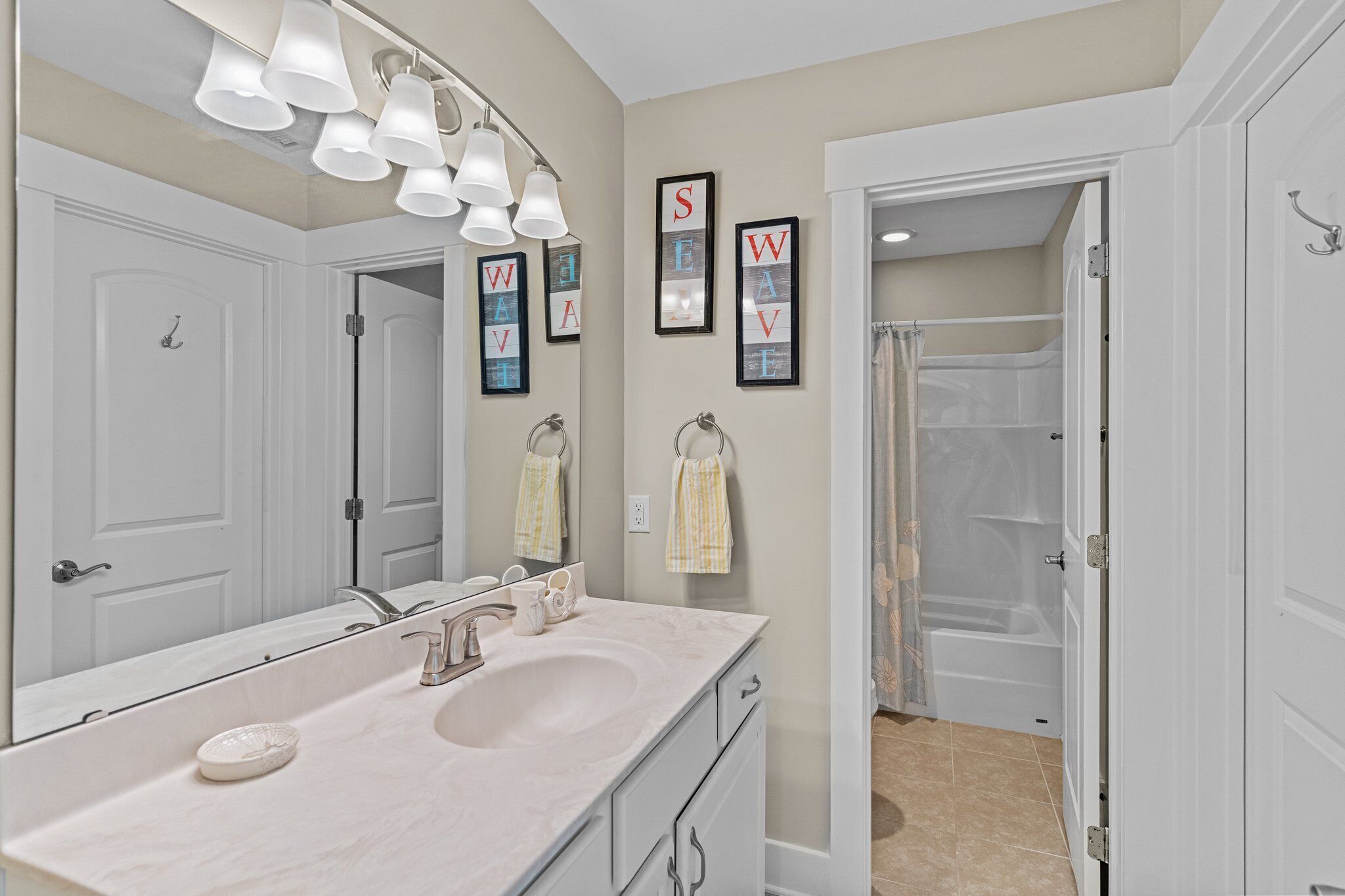 Une salle de bain avec un grand miroir, un lavabo et un espace douche.