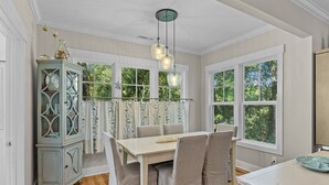 Un coin repas avec une table blanche, des chaises grises et un buffet aux portes vitrées.