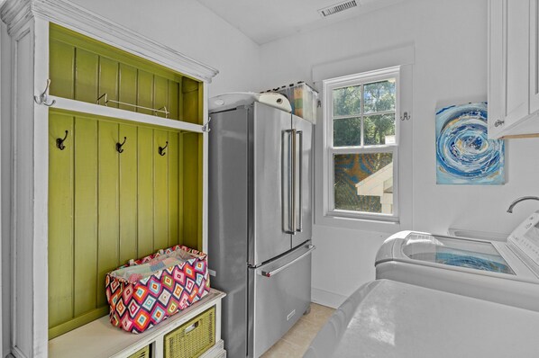 A compact kitchen with a stainless steel refrigerator, a window with a view, and a laundry area.