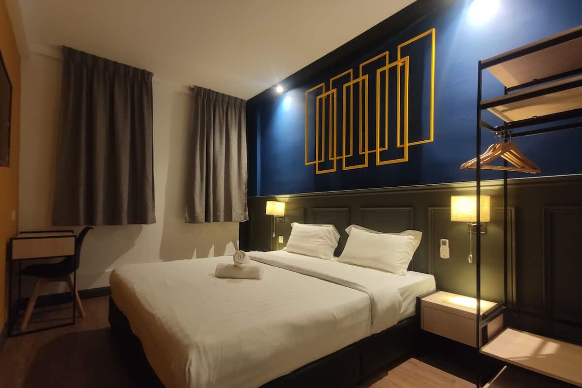 A hotel room with a large bed, bedside tables, a desk, and a chair.