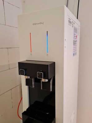 Een waterdispenser met twee kraan, een rode en een blauwe, en een zwarte koeler eronder.