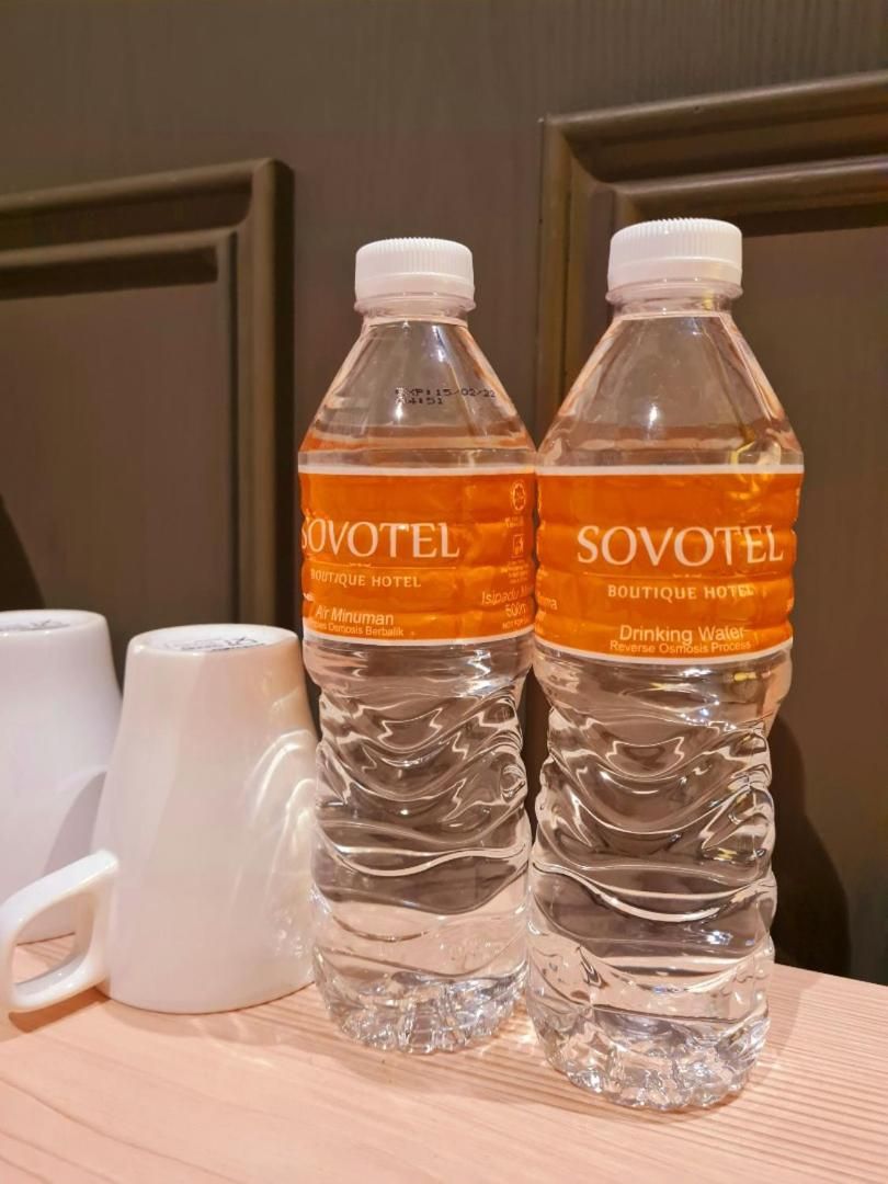 Deux bouteilles d’eau minérale SOVOTEL et deux tasses blanches sur une surface en bois.