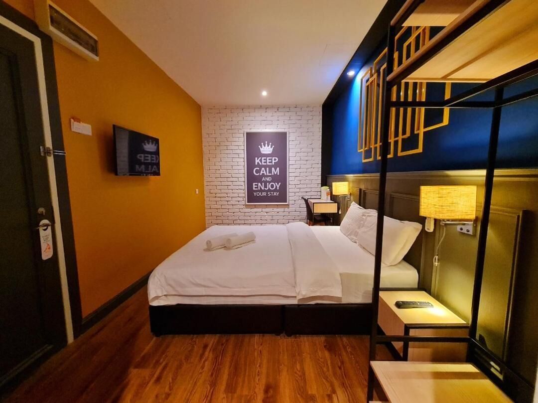 Une chambre d’hôtel équipée d’un lit, d’une télévision, d’un panneau fixé au mur et d’une table de chevet avec une lampe.