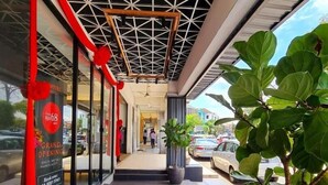 Entrada de hotel con piso de baldosas, una planta en maceta y una decoración con cinta roja.