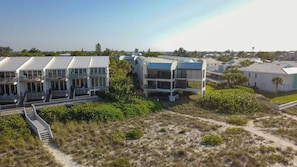 A coastal hotel with multiple-story buildings, balconies, and a sandy landscape.