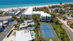 Eine Luftaufnahme eines Hotels an der Küste mit Strand, Tennisplatz und Schwimmbad.