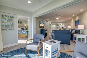 A spacious living area with a sofa, chairs, a coffee table, and a kitchen in the background.