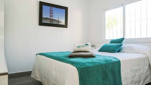 Une chambre d’hôtel avec un lit, une fenêtre et un tableau représentant le pont du Golden Gate.